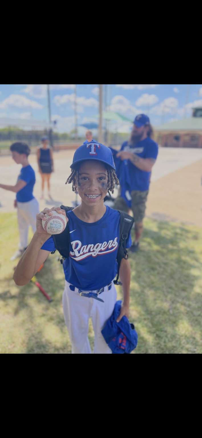 Morgan smiling in his Rangers uniform while holding the game ball from his first baseball game